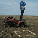 Jeremy standing on the back of a quad and using binoculars.